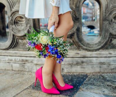 woman holding white, blue, and red petaled flower bouquet beside gray concrete fence