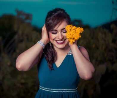 woman touching her hair while holding orange flowers