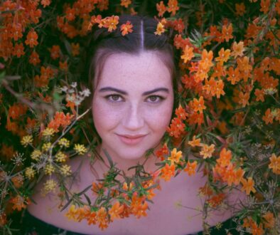 woman in black shirt surrounded by brown leaves