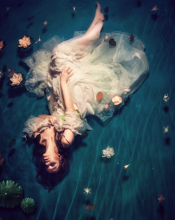 woman wearing dress and lying on teal cloth