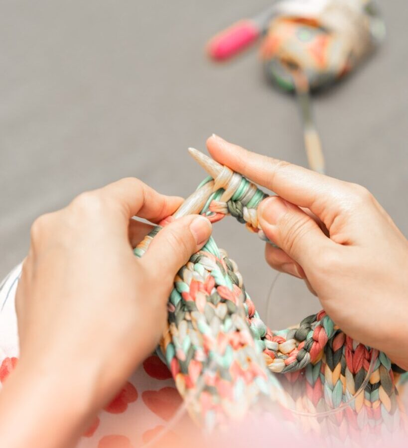 a woman is knitting a piece of fabric