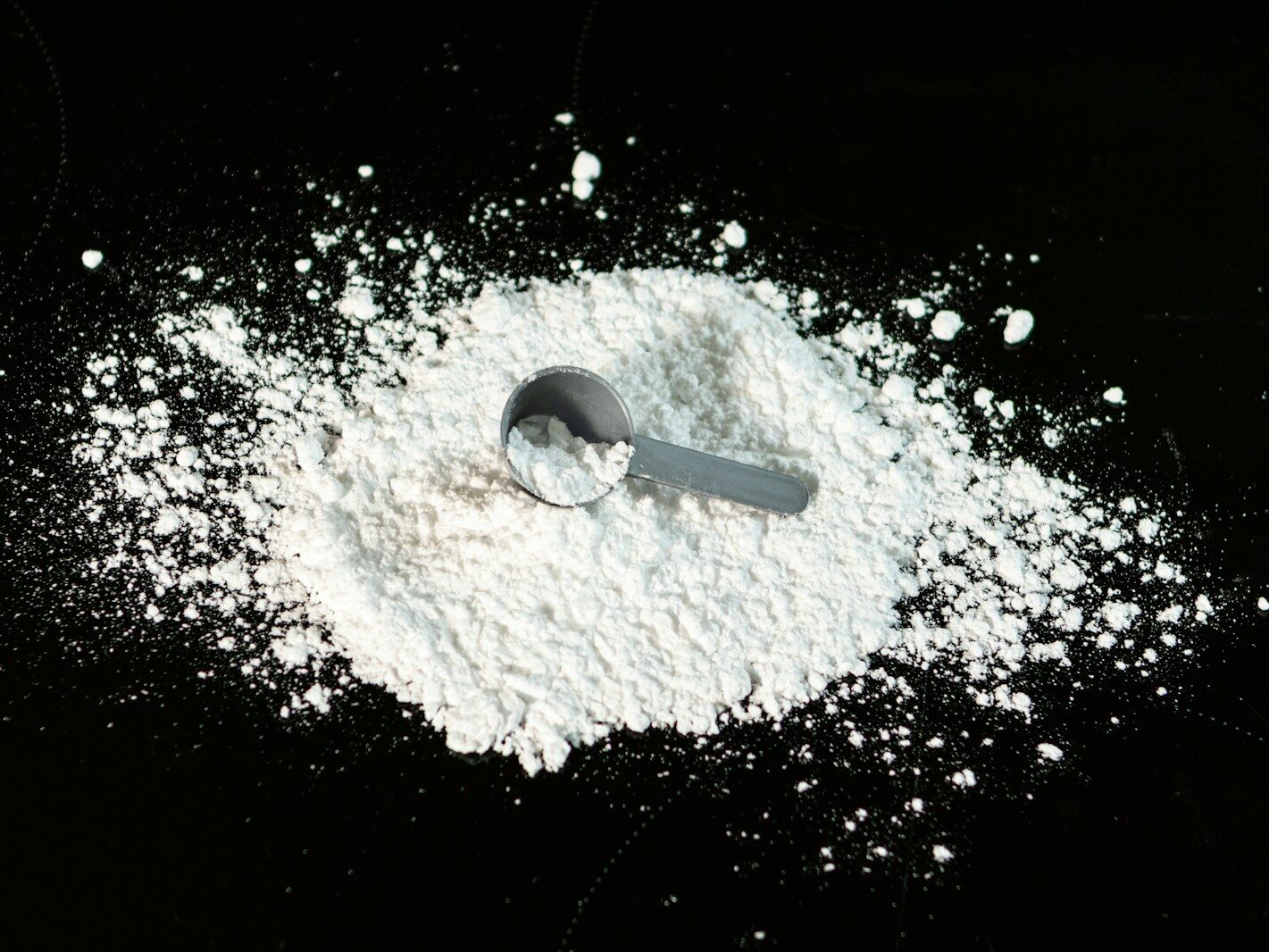 a scoop of powder next to a scoop of sugar
