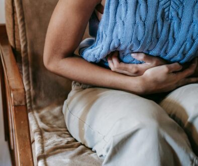 Crop unrecognizable female touching belly while having acute pain in stomach sitting on couch