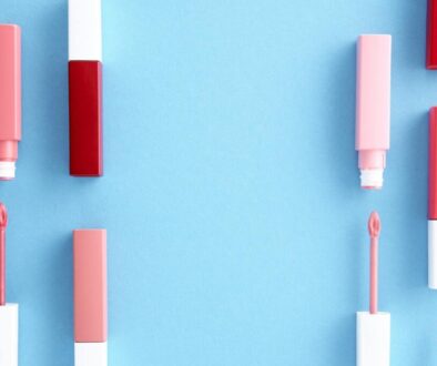 Colorful lip gloss tubes laid out on a bright blue background, showcasing modern cosmetics.