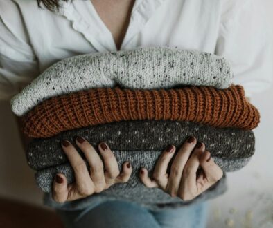 A Close-up Shot of a Person Holding a Stack of Folded Knitted Fabrics