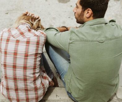 A couple sitting on the street, engaged in a distressed conversation, capturing a moment of emotional tension.