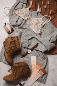 Flat lay of neutral fashion essentials including boots, bra, and color palette for a stylish outfit.
