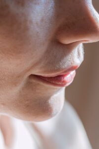 Sunlit close-up of a woman's lips and nose highlighting skin texture.