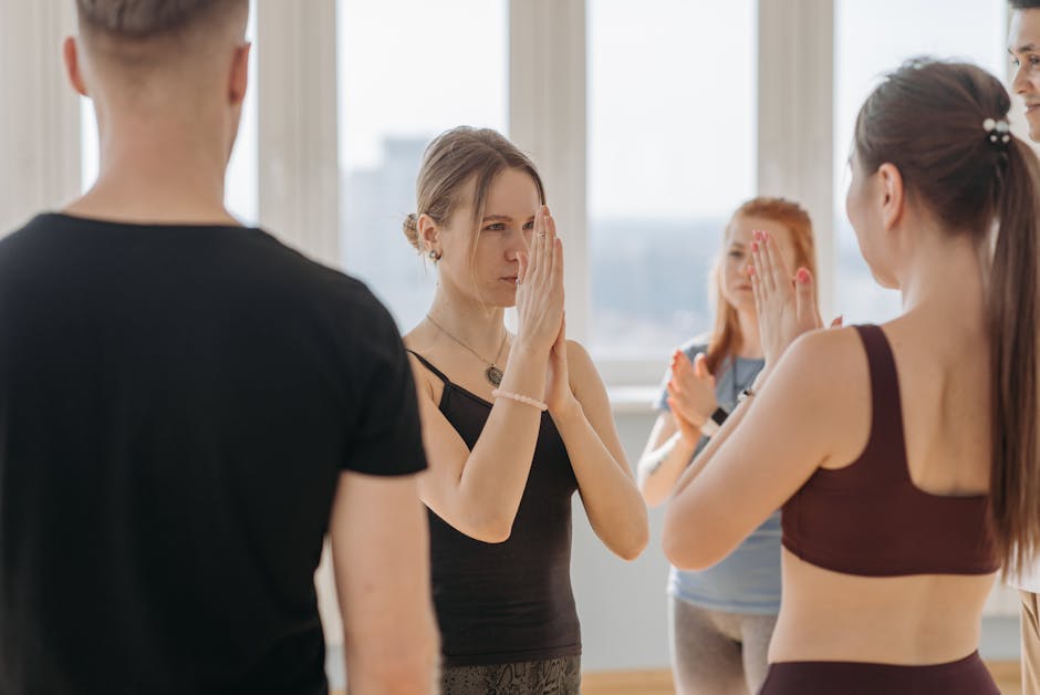 A group of adults practicing yoga together in a bright indoor studio setting.