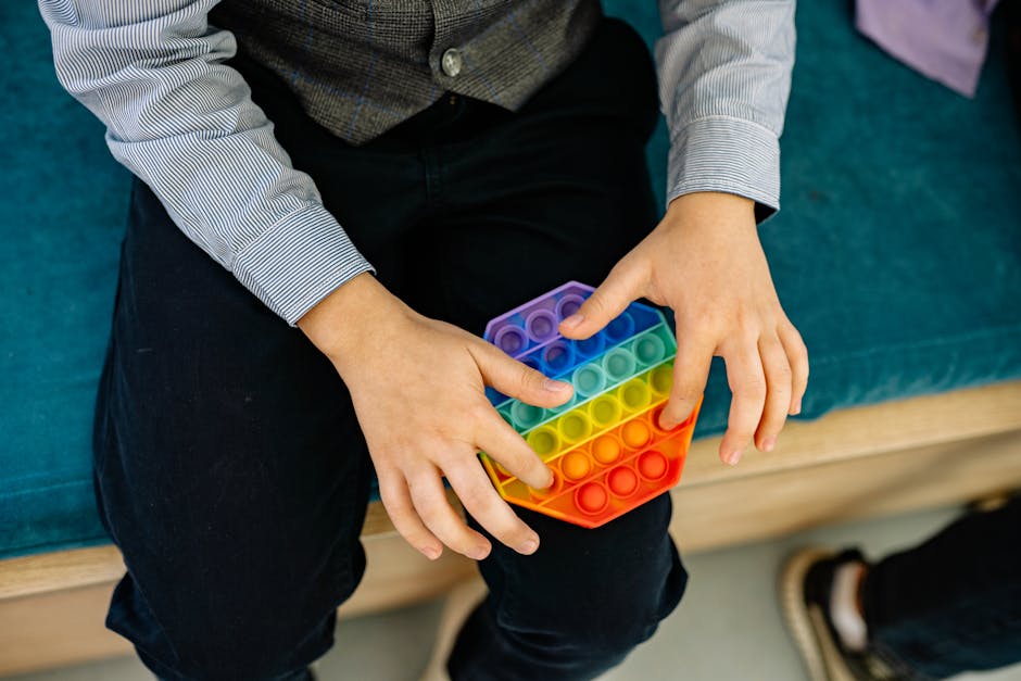 A child's hands engaging with a rainbow pop it fidget toy, promoting sensory play.