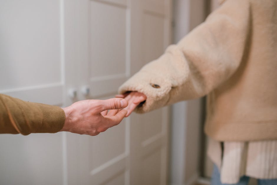 Close-up of two people holding hands indoors, indicating connection and support.