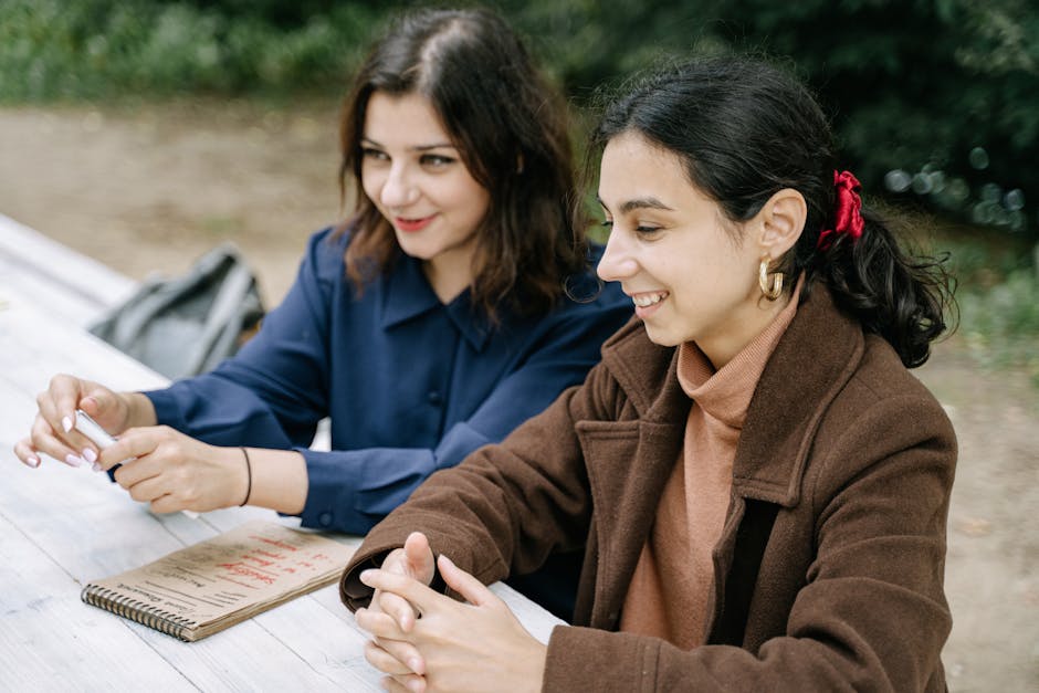 Two women chat and enjoy leisure time together at an outdoor table.