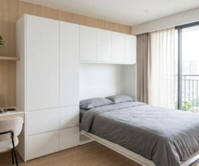 Minimalist bedroom with a low gray bed, white storage cabinets, and a desk by a large window overlooking a cityscape.Screenshot-free alt text should convey function and scene: concise and descriptive.