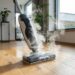 Steam mop in use on a wooden floor, releasing steam as it cleans a modern living room with plants and large windows