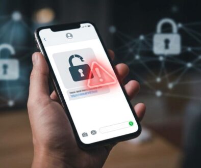 Hand holding a smartphone displaying a security alert icon (padlock with warning) against a blurred digital network background.