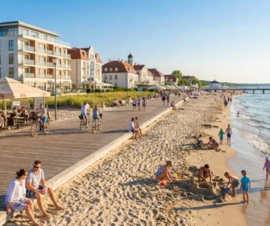 Beachfront promenade with cafes and outdoor dining, cyclists on the boardwalk, and families playing on the sandy shore.