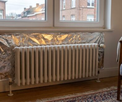 White radiator under a window with crumpled aluminum foil insulation behind it in a living room.