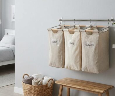 Laundry sorting system with labeled fabric bags (DARKS, LIGHTS, DELICATES) hanging on a wall rod in a bright bedroom.