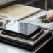 Chef chopping parsley on a marble cutting board in a stainless steel kitchen.