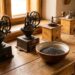 Row of antique manual coffee grinders on a wooden counter with a bowl of coffee beans nearby.