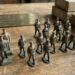 Assorted Elastolin toy soldiers lined up on a wooden table with boxes in the background.