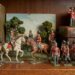 Vintage toy soldiers and cavalry figures arranged on a wooden shelf with antique books in the background.
