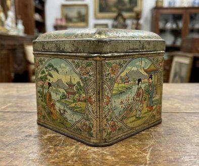 Decorative metal tin with oriental landscape panels and floral borders, square with a lid (vintage Asian-inspired design).