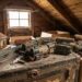 Dusty attic with a row of antique toy trains on a weathered trunk and cardboard boxes nearby.
