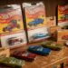 Row of vintage Hot Wheels die-cast cars in red, blue, and green on a wooden shelf with packaging visible behind them.