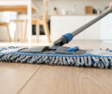 Close-up of a flat mop cleaning a wooden floor in a bright kitchen.