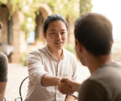 A diverse group outdoors shaking hands, signaling agreement or collaboration during a sunny meetup.