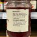 Jar of red fruit jam on a store shelf with a beige label listing ingredients and 25% fruit content in clear print.