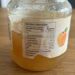 Jar of peach jam on a wooden table with the nutrition information label clearly visible on the front edge.