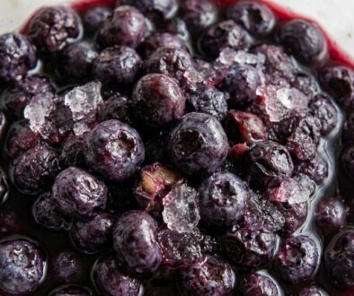 Close-up of frozen blueberries in a glass container with ice crystals and a purple juice around them.