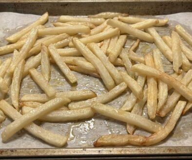Tray of light golden baked French fries on parchment paper