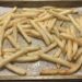 Tray of light golden baked French fries on parchment paper