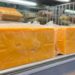 Blocks of orange cheddar cheese in clear plastic wrap on a supermarket dairy shelf