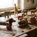 Row of vintage wooden toys on a worn workbench: spring dog pull toy, train cars, giraffe, and elephants.