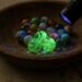 Wooden bowl with colorful marbles glowing green under a UV flashlight.