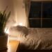 Dimly lit bedroom at night with a snake plant on a wooden nightstand beside a bed.