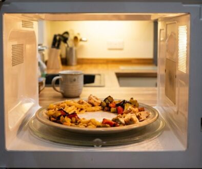 Plate with mixed vegetables and chicken reheating on a microwave turntable in a kitchen.