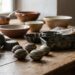 Vintage metal baking molds scattered on a wooden table with ceramic bowls in the background by a sunlit window.