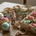 Assorted vintage Christmas ornaments on a rustic wooden table, including a Santa figure, glass baubles, a metal bird, and a bead garland in a box.