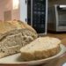 Loaf of crusty bread on a plate in a kitchen, with a toaster oven and microwave in the background.