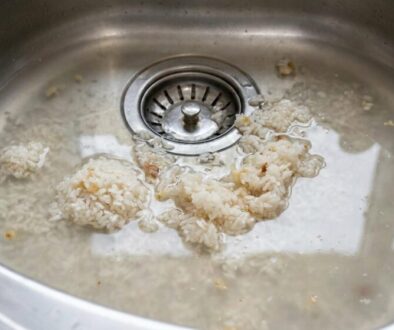Rice clumps soaking in a stainless steel kitchen sink around the drain
