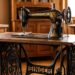 Vintage Singer treadle sewing machine on a carved iron table in a sunlit wood-filled room.